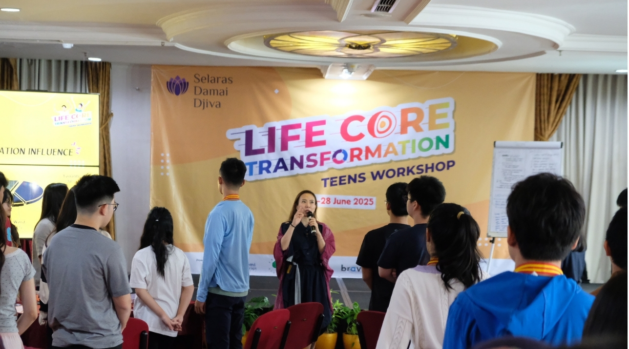 Pembicara wanita berbaju navy memegang mikrofon saat sesi presentasi